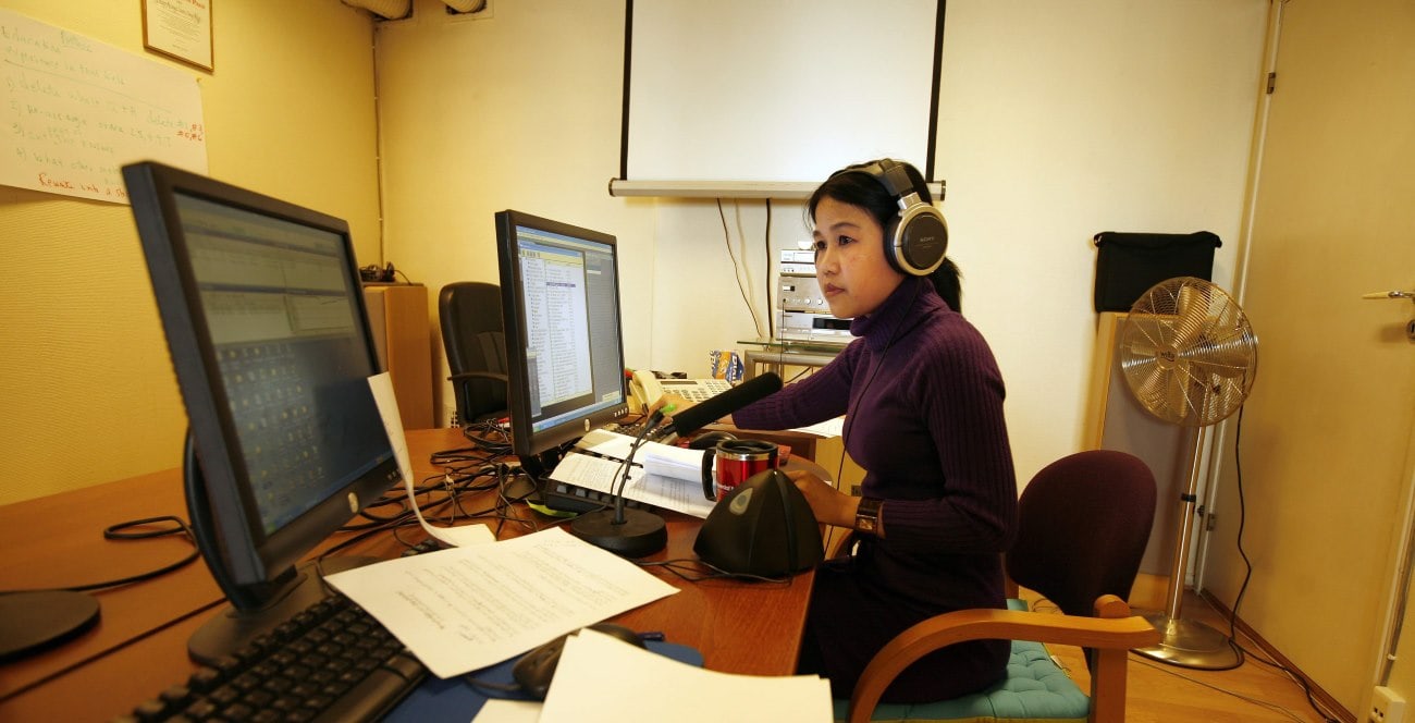 a woman with headphones at a desk on a computer