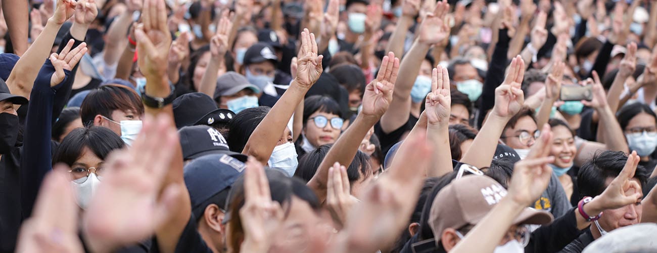 Pro democracy protestors in Thailand raising the three finger gesture