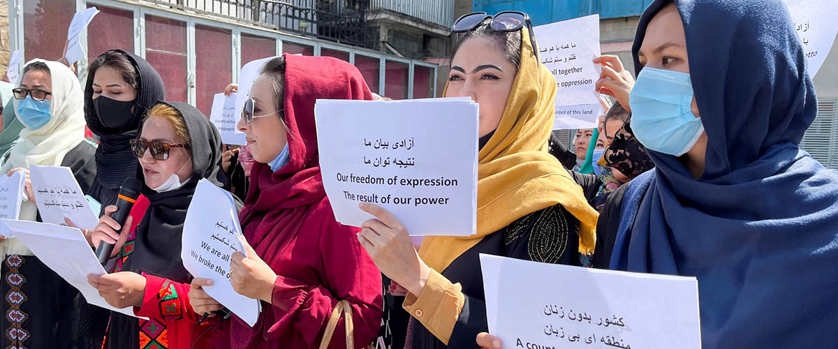 Aghan women hold up banners protesting in favour of freedom of expression
