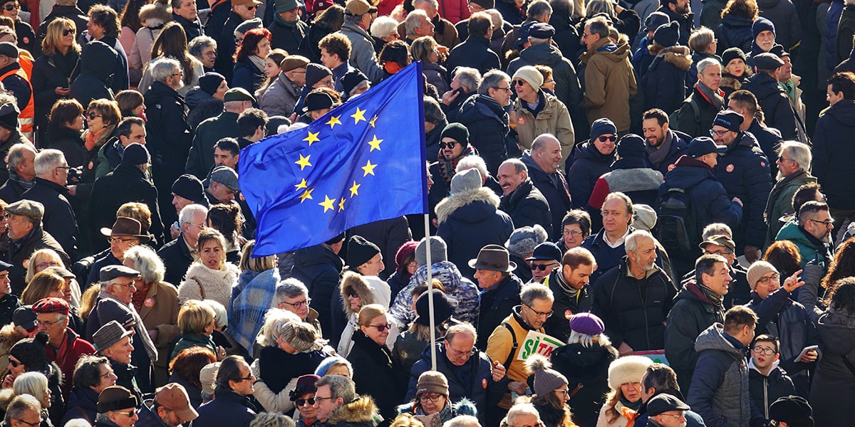 A pro EU demonstration in Italy where a member of the crowd holds up an EU flag int he centre of the image